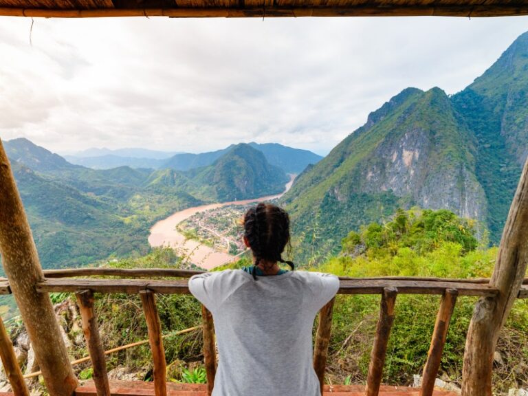 800 - Laos für Entdeckerwoman-on-wooden-balcony-conquering-mountain-top-at-nong-khiaw-nam-ou-river-valley-laos
