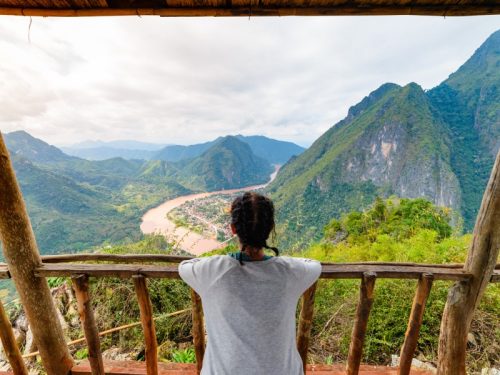 800 - Laos für Entdeckerwoman-on-wooden-balcony-conquering-mountain-top-at-nong-khiaw-nam-ou-river-valley-laos