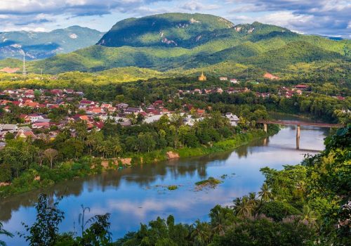 View of Luang Prabang and Nam Khan river in Laos with beautiful sunset light bathing the background mountains