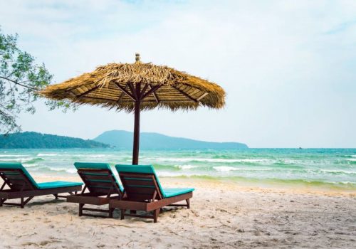 800 - RI-K-5-001two-chaise-longues-under-a-straw-umbrella-on-a-beach-near-the-sea-tropical-background-coast-of-island-koh-rong-samloem-cambodia