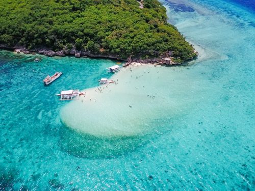 Aerial view of sandy beach with tourists swimming in beautiful clear sea water of the Sumilon island beach landing near Oslob, Cebu, Philippines. - Boost up color Processing.